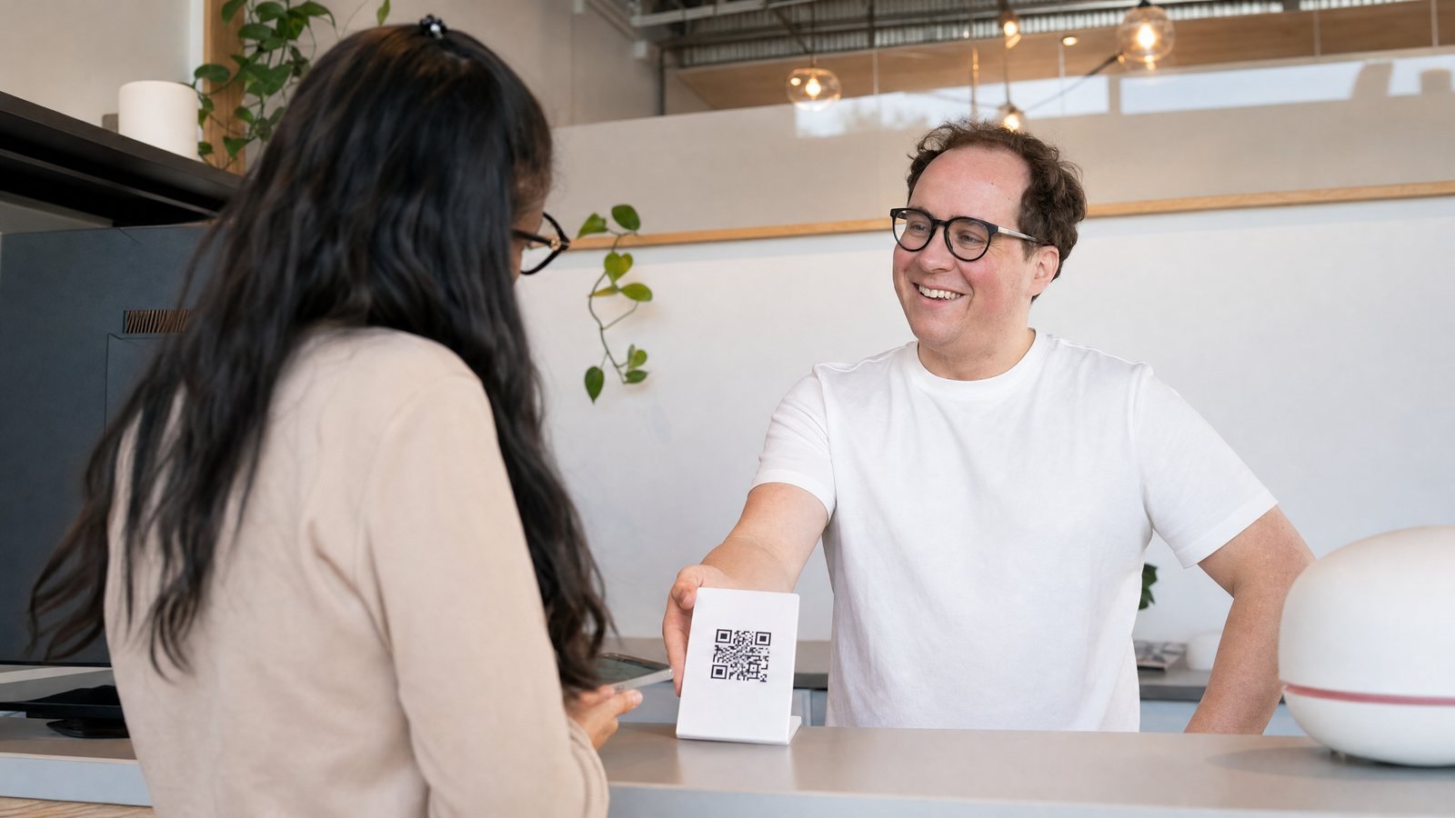 Commerçant qui montre un QR code affiché en caisse à un client pour lui demander un avis Google